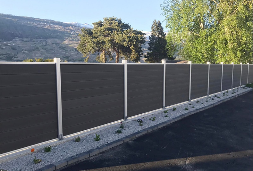 mexytech dark gray composite fence installed along a driveway with aluminum posts and mountain landscape background